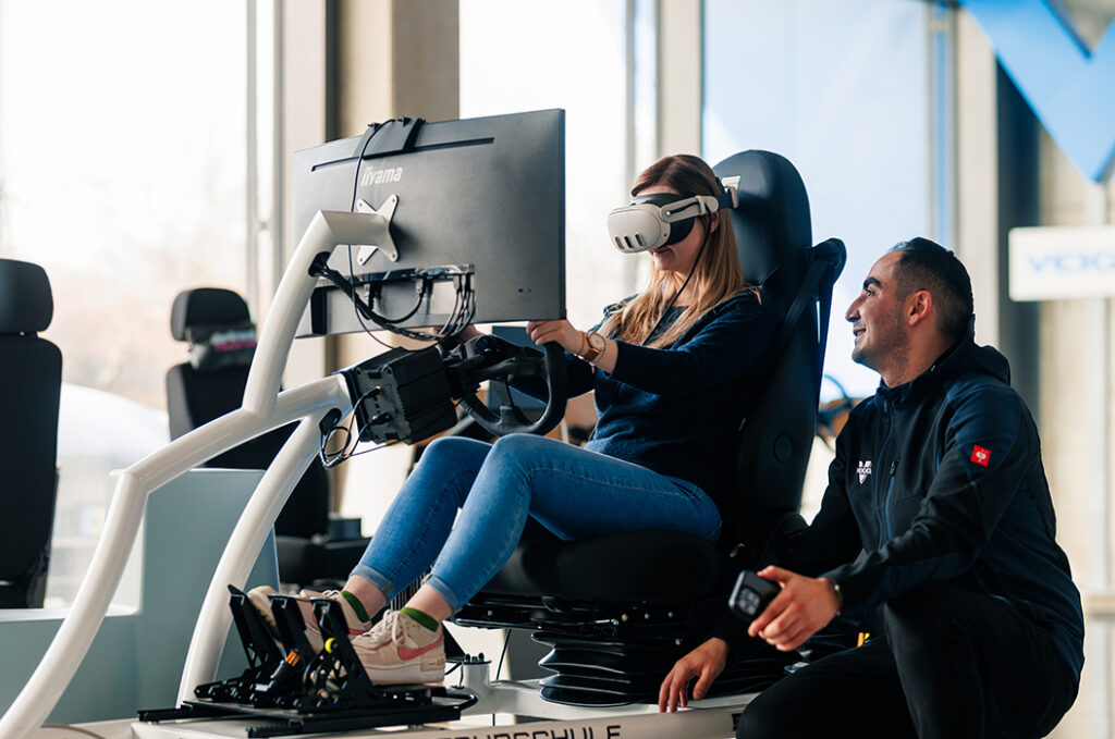 Eine Frau mit VR Brille und blonden Haaren spielt Rennsimulation am Simulator, lächelt