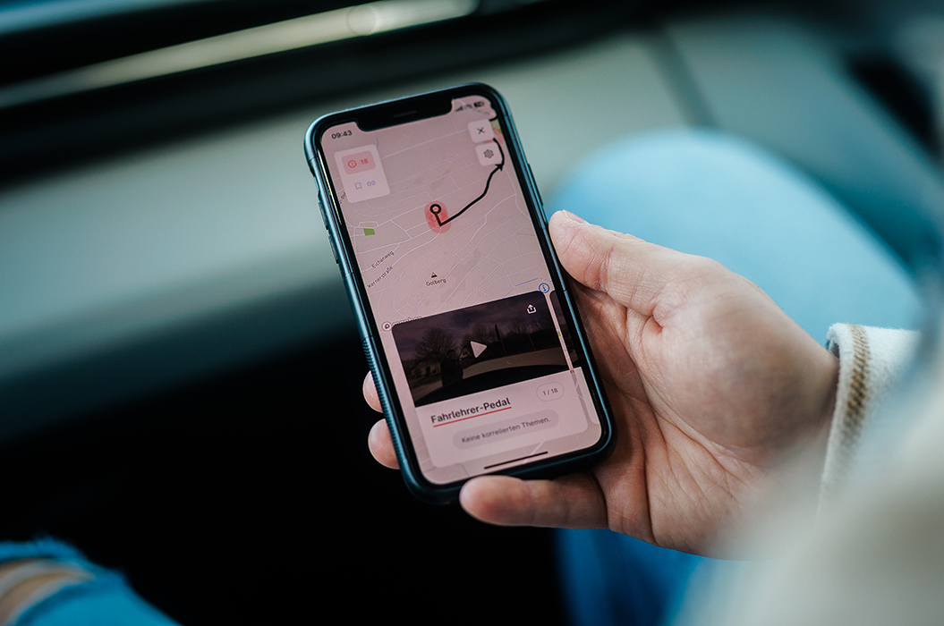 Eine Person mit heller Haut hält ein schwarzes Smartphone mit Kartennavigation in der Hand